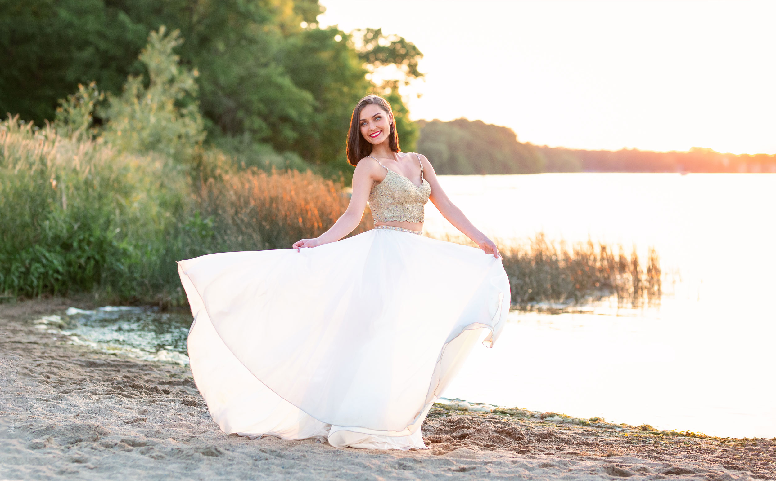 Girl in formal dress twirling by lake